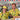 Two people wearing matching yellow shirts with a brand logo in a casual setting.