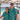 Two people wearing matching teal shirts with boat patterns at a beachside event.