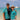 Two people in matching turquoise shirts with a beach and ocean background