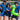 Three people in matching blue uniforms holding drinks and an inflatable crocodile on a beach.