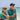 Two people in matching blue shirts with a beach and ocean background