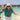 Person on a beach wearing a colorful shirt and hat with a scenic background